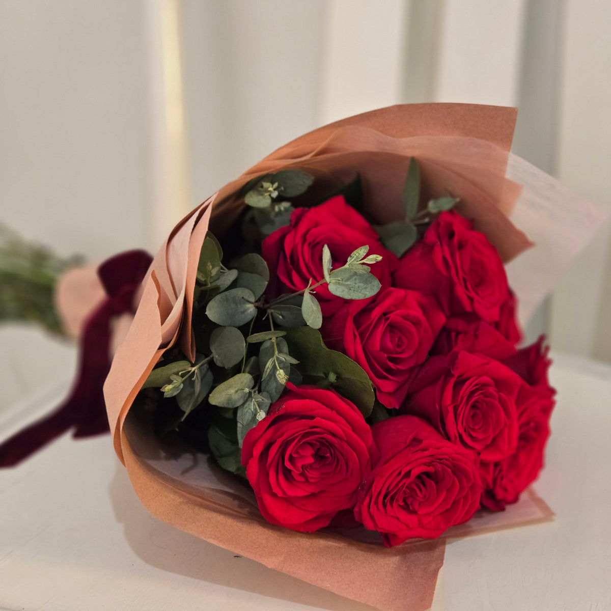 Bouquet of red roses wrapped in luxury waterproof paper against a neutral background Delivery Fairfield and Vedder