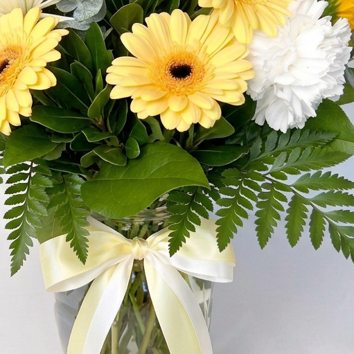 Bouquet of orange and white flowers in a clear vase with an orange ribbon on a light background. Delivery in Chilliwack Cultus Lake and Sardis.