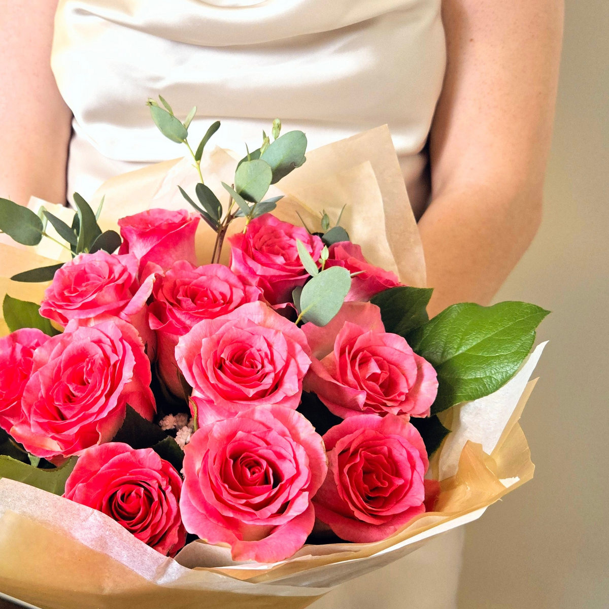 Bouquet of pink roses held by a person wearing a white  satin dress. Luxuriously wrapped premium roses for delivery in Chilliwack and Fairfield Island BC